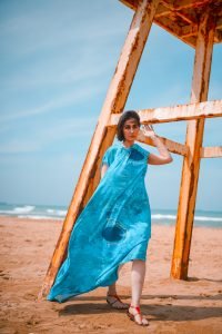 Woman posing in a long, blue maxi dress on the beach